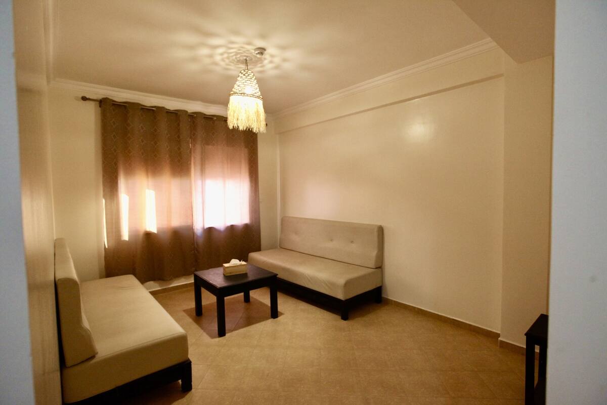 A living room with a sofa, a small table, and a ceiling light fixture.