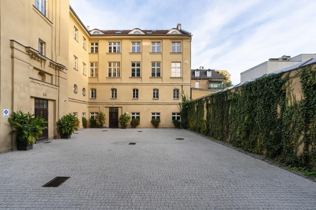Un cortile con un edificio dalla facciata simmetrica, diverse finestre e un ingresso centrale.