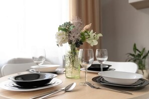 A dining table set with plates, cutlery, and glasses, accompanied by a vase of flowers. - Stylish Apartment in Jeżyce | Balcony | Close to MTP (Poznan)