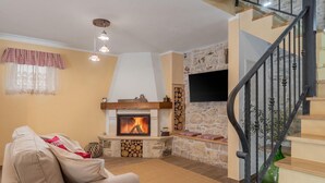 A cozy living room with a fireplace, a sofa, and a staircase.