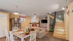 A modern kitchen with a dining area, a fireplace, and a staircase leading to an upper level.