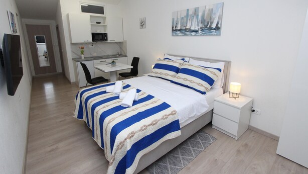 Un dormitorio con cama, mesita de noche y escritorio con silla.