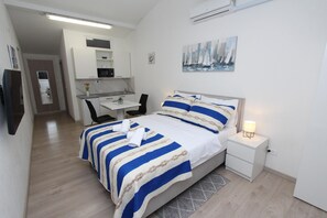 A bedroom with a bed, bedside table, and a desk with a chair. - Studio Sunny (Rovinj)