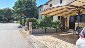 Entrada de hotel con porche cubierto, sendero de piedra y un coche estacionado cerca.