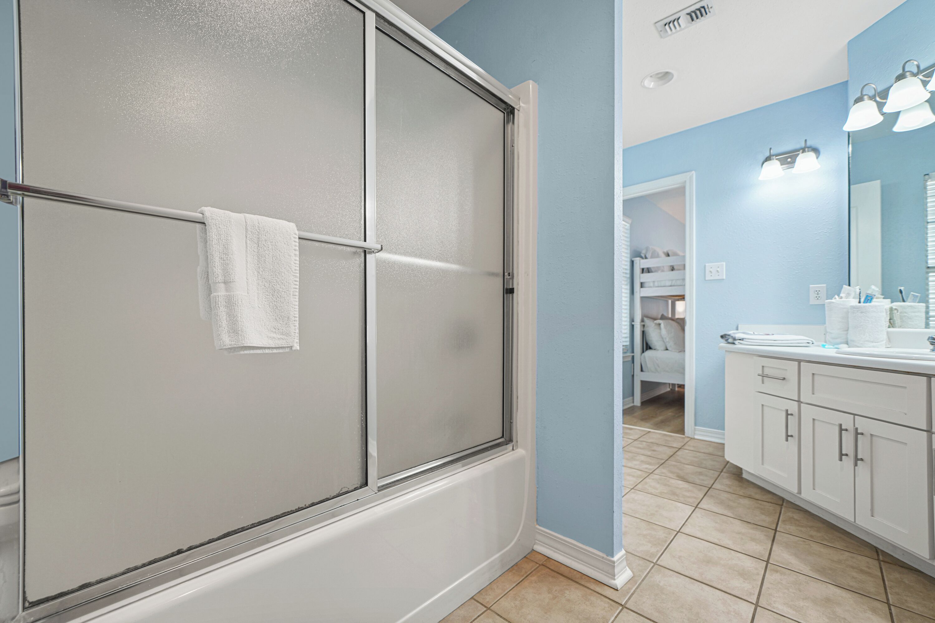 Bright shared bathroom connected to the bunk room, featuring a tub/shower combo, spacious vanity, and fresh towels. Convenient layout with easy access for kids or additional guests.