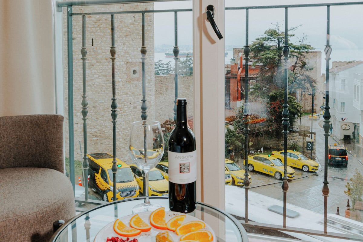 A glass table with a bottle of wine, a glass, and a plate of fruit.