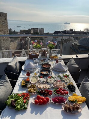 A table set with a variety of dishes and drinks, overlooking a body of water with a distant ship. - Joyway Hotels Istanbul Sultanahmet (Istanbul)