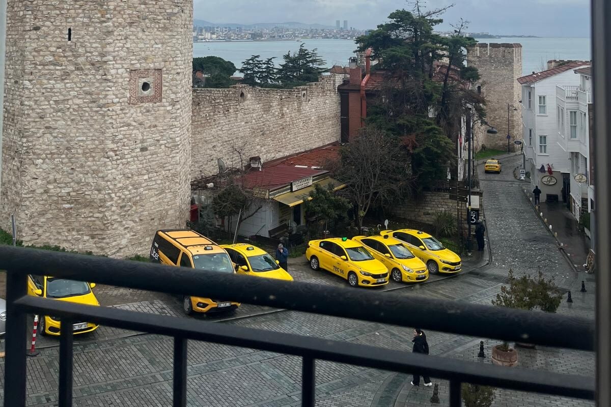 Blick auf einen historischen Steinturm und eine Straße mit gelben Taxis.