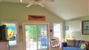 A living room with a ceiling fan, a sofa, a chair, and a television. - Short Distance to Colonial Acres Beach (2342) (West Yarmouth)