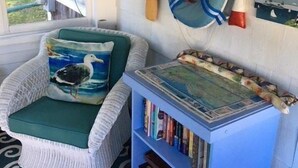 A cozy room with a wicker chair, a bookshelf, and various wall decorations including a fan, a fish, and a paddle. - Short Distance to Colonial Acres Beach (2342) (West Yarmouth)