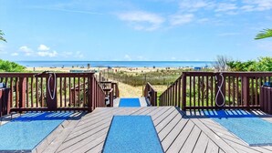 Eine Holzterrasse führt zu einem Strand mit freiem Blick auf das Meer und den Sandstrand.