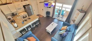 A compact living space with a kitchenette, a dining area, a sofa, and a television. - Oyster Cove (Port Isabel)