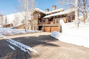 Un grand chalet à plusieurs étages, doté d’un balcon imposant et d’un toit recouvert de neige.