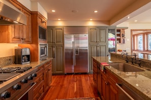 A modern kitchen with wooden cabinets, stainless steel appliances, granite countertops, and a built-in oven.