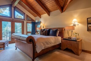 Une chambre avec un grand lit, une tête de lit en bois, des lampes de chevet et une vue sur l’extérieur.