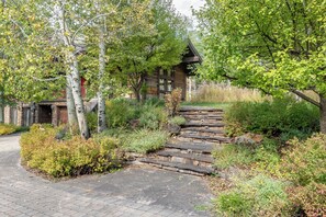 A stone staircase leading to a wooden cabin surrounded by lush greenery and trees. - Canyon Run Home - Upscale 5BR Ketchum Home with Yard and Sauna (Ketchum)