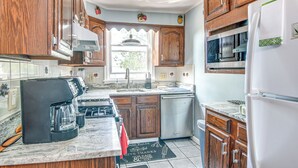 A kitchen with wooden cabinets, a stainless steel dishwasher, a black coffee maker, and a tiled backsplash. - Quaint Lansdowne Getaway Near Downtown Philly! (Lansdowne)