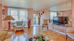 A living room with a television, two armchairs, a coffee table, and a large vase with flowers. - Quaint Lansdowne Getaway Near Downtown Philly! (Lansdowne)