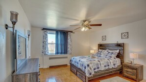 A bedroom with a wooden bed, a ceiling fan, a nightstand, a dresser, and a window with curtains. - Quaint Lansdowne Getaway Near Downtown Philly! (Lansdowne)