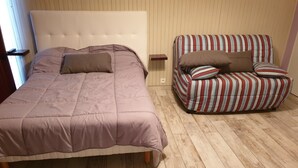 Een slaapkamer met een bed, een gestreept sofa en een houten vloer.