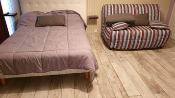 Een slaapkamer met een bed, een gestreept sofa en een houten vloer.