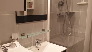 Een moderne badkamer met een wit wastafel, een spiegel, een douchecabine van glas en een toilet.