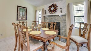 A dining room with a large wooden table surrounded by ornate chairs, a fireplace, and a framed picture on the wall. - Orlando Home: 6 Mi to Universal! (Orlando)