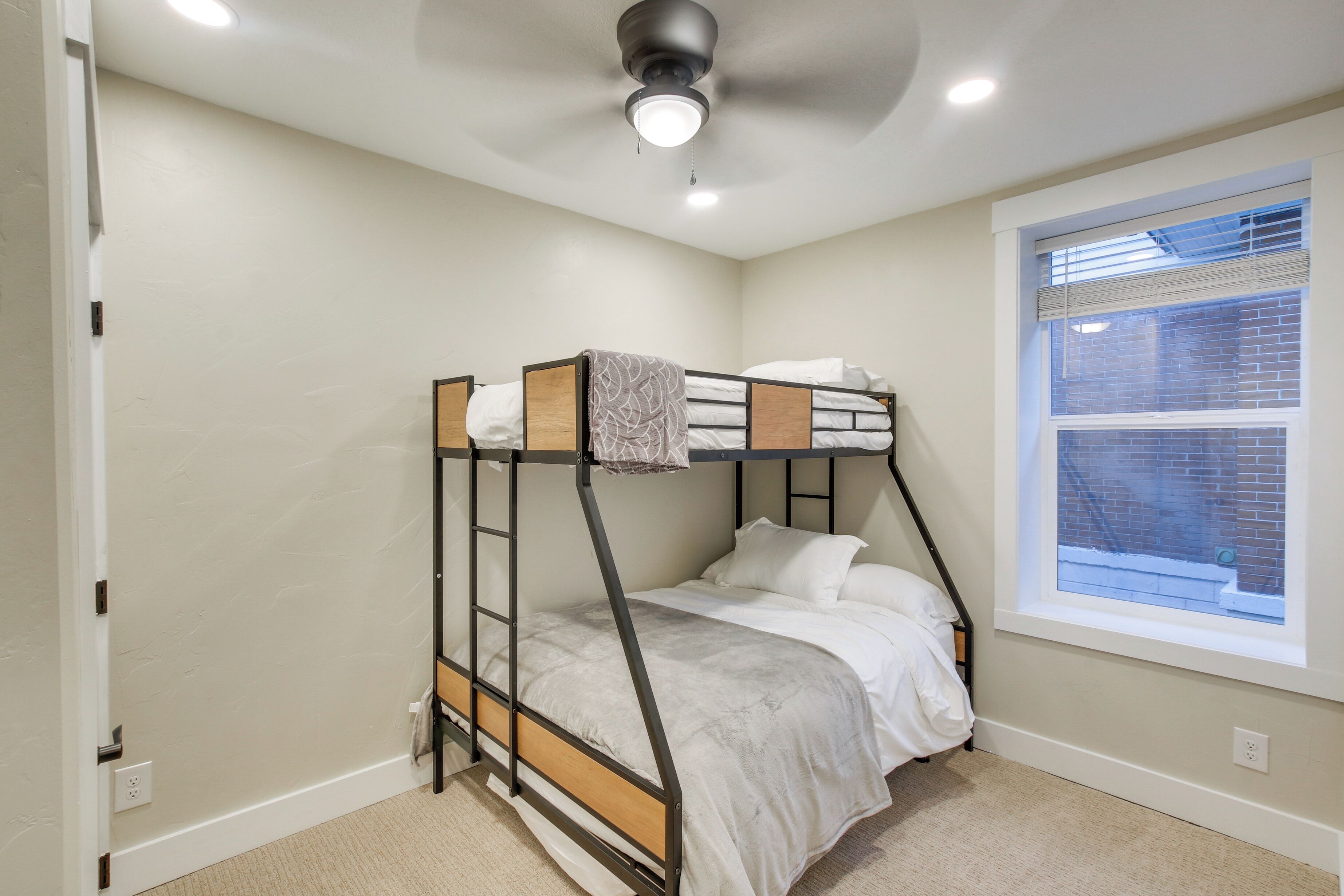 A bunk bed in a room with a window, a ceiling fan, and a light fixture.