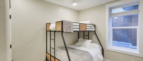 A bunk bed in a room with a window, a ceiling fan, and a light fixture.