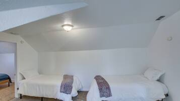 A small, white-walled room with two single beds, each with a patterned blanket.