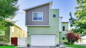 A two-story residential building with a garage door, a small window on the upper floor, and a green lawn. - South Salt Lake Home w/ Hot Tub: 7 Mi to Downtown (Salt Lake City)