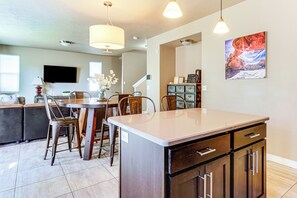 A modern kitchen with a central island, dining chairs, a chandelier, and a large window. - South Salt Lake Home w/ Hot Tub: 7 Mi to Downtown (Salt Lake City)