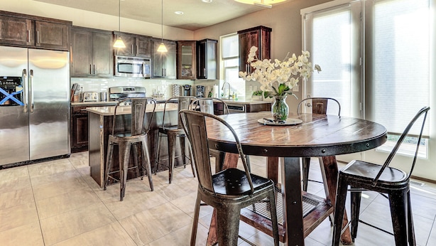A modern kitchen with dark wood cabinets, stainless steel appliances, and a dining area with a round table and chairs. - South Salt Lake Home w/ Hot Tub: 7 Mi to Downtown (Salt Lake City)