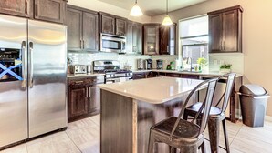 A modern kitchen with dark wood cabinets, stainless steel appliances, and a central island with bar stools. - South Salt Lake Home w/ Hot Tub: 7 Mi to Downtown (Salt Lake City)