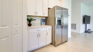 A modern kitchen with white cabinets, a stainless steel refrigerator, and a potted plant on the countertop. - Airy Port Charlotte Home w/ Smart TV Near Beaches! (Port Charlotte)