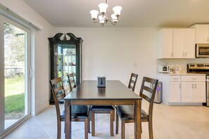 Un comedor con una mesa y sillas de madera, un candelabro y vistas al exterior a través de un ventanal.