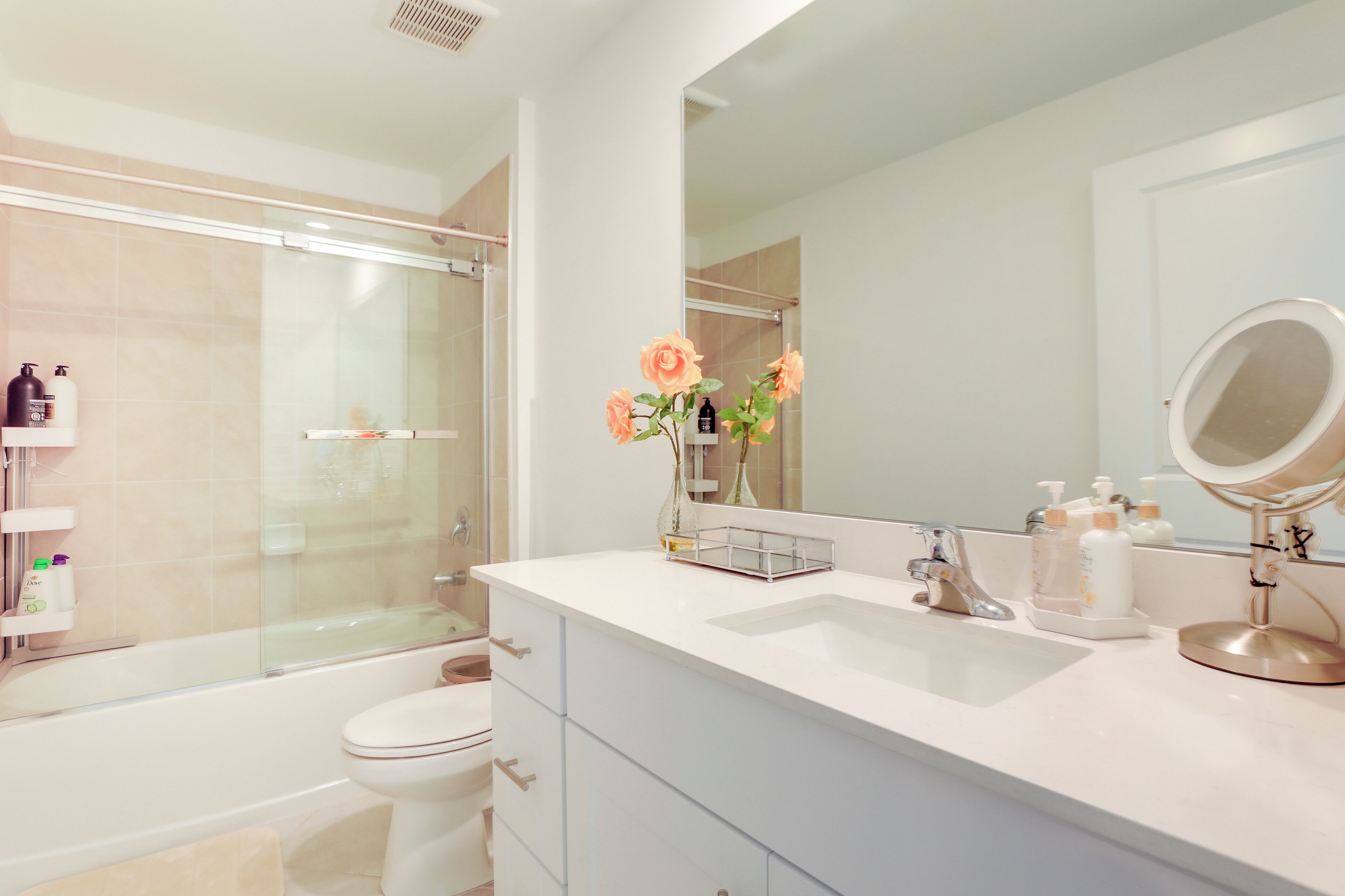 Un baño moderno con cabina de ducha de vidrio, un lavabo blanco con mueble y un espejo grande.