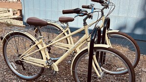 Una bicicleta estacionada sobre grava, con un muro azul al fondo.