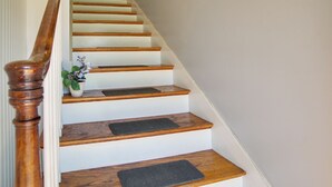 Una escalera de madera con una pared blanca y una puerta al final.