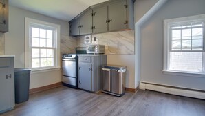 Una cocina equipada con microondas, estufa, refrigerador y basurero.