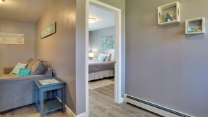 Une pièce comprenant un lit, une petite table et une étagère fixée au mur, ornée d’objets décoratifs.