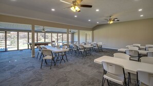 A spacious room with multiple tables and chairs, ceiling fans, and large windows offering a view of the outdoors. - Lafollette Home: Community Pool & Mountain Views! (La Follette)