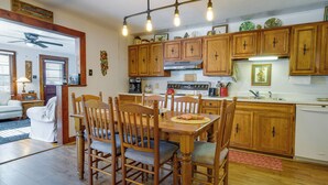 A dining area with wooden chairs and a table, a kitchen with wooden cabinets and appliances, and a ceiling fan. - Pet-friendly Topton Home w/ Patio, Deck & Views! (Topton)