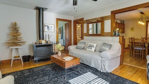 A living room with a sofa, coffee table, and a fireplace. There is a dining area with a table and chairs visible through an open doorway. - Pet-friendly Topton Home w/ Patio, Deck & Views! (Topton)