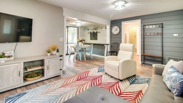 A modern living room with a sofa, a TV, and a dining area with a table and chairs.