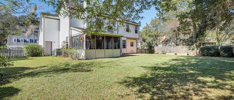 A two-story house with a covered patio, a well-maintained lawn, and a wooden fence.
