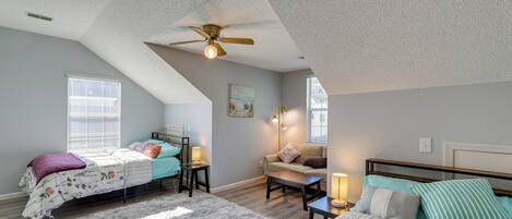 A bedroom with two beds, a ceiling fan, and a large window.