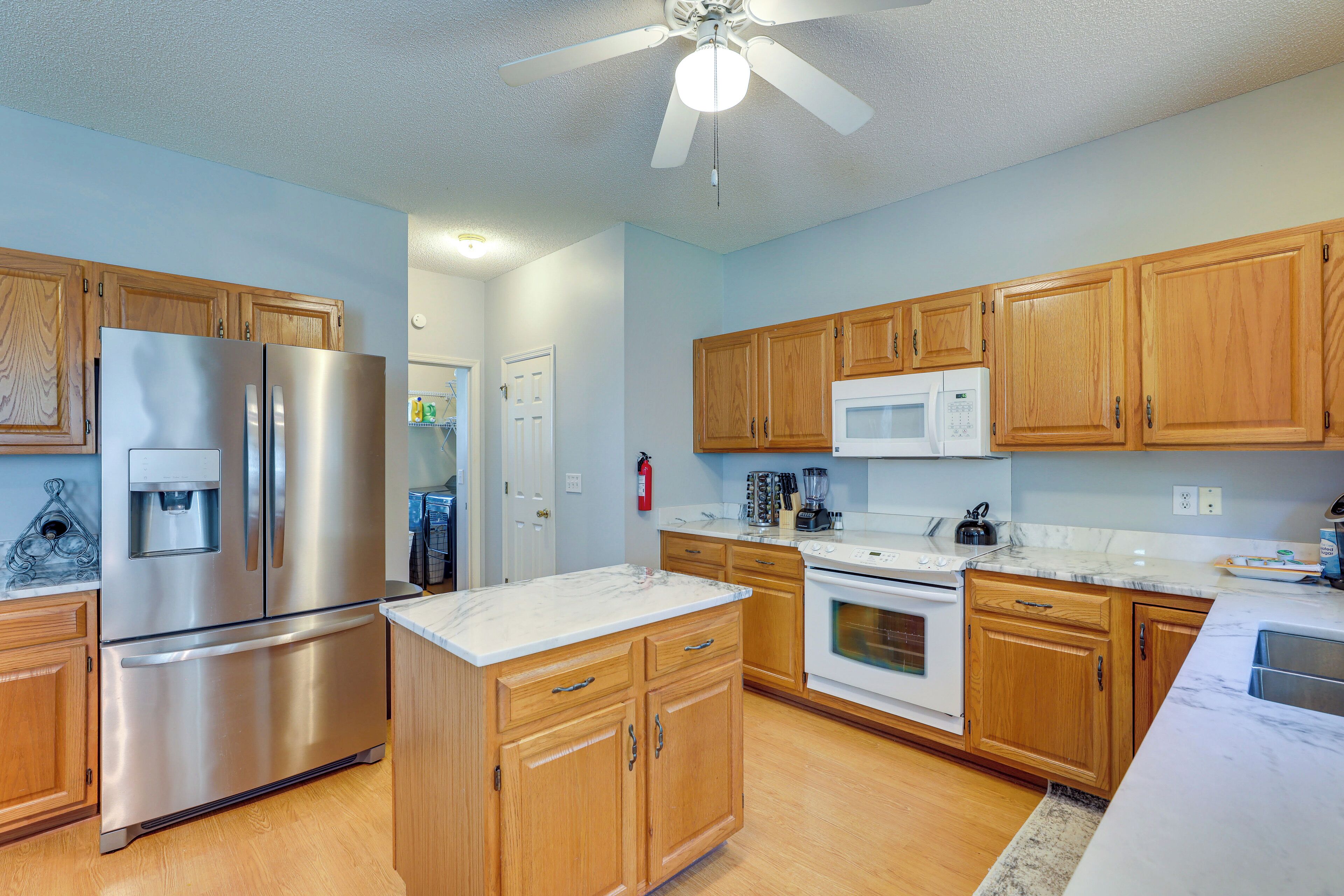 A modern kitchen with wooden cabinets, stainless steel appliances, and a white countertop.