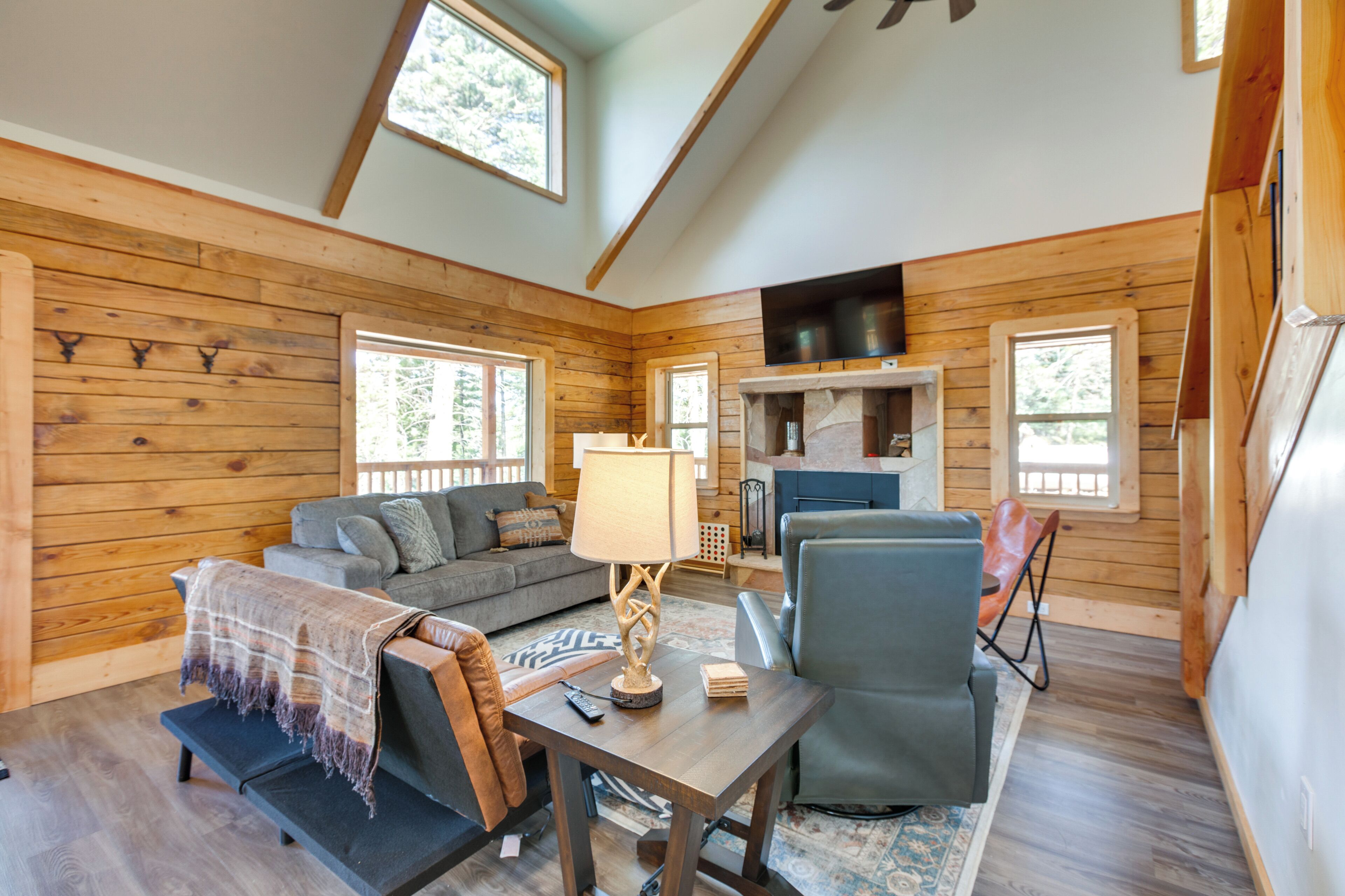 L’intérieur d’un chalet accueillant, avec des murs en bois, une cheminée, un canapé, une table et une chaise.