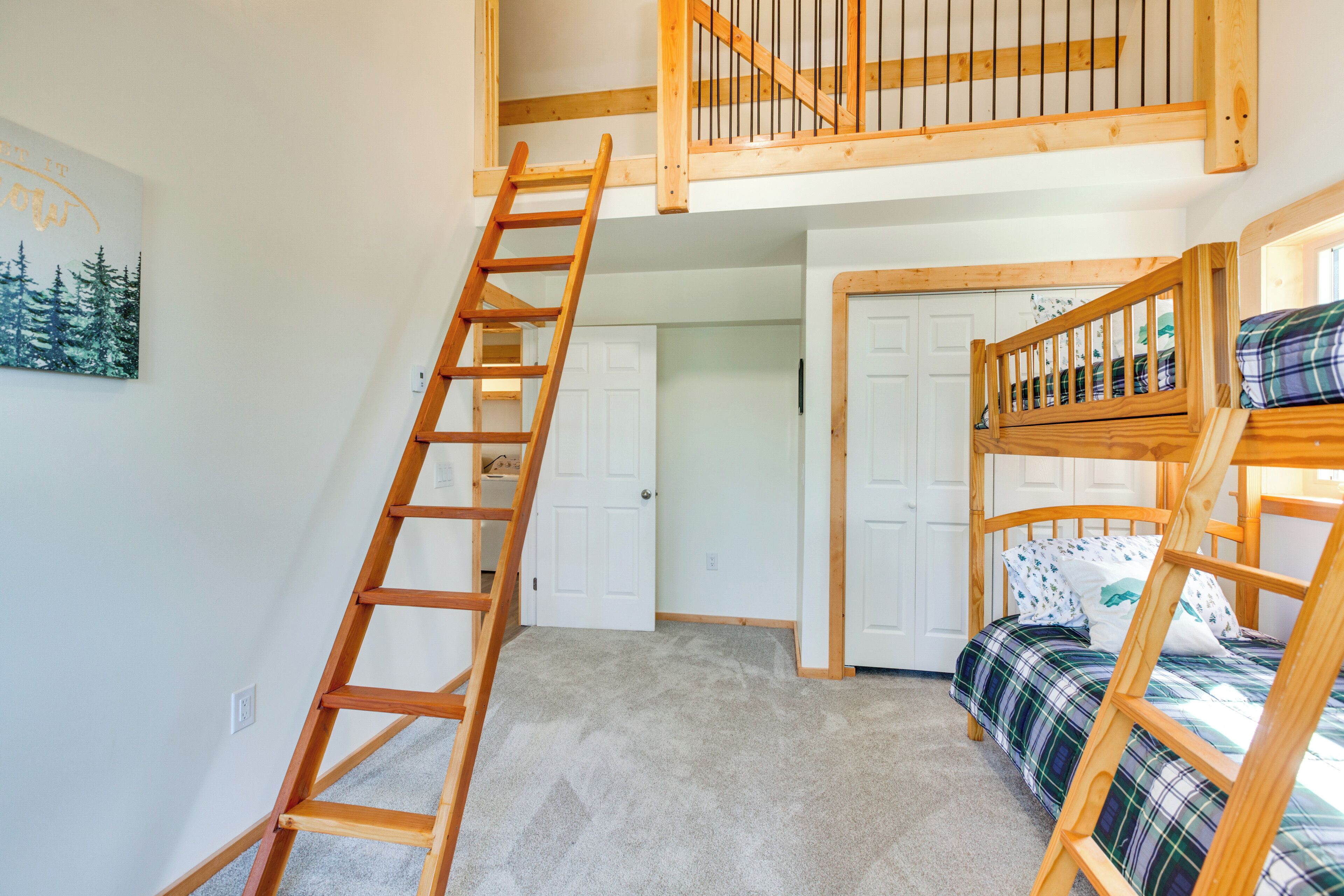 A bedroom with bunk beds, a wooden ladder, and a door leading to another room.